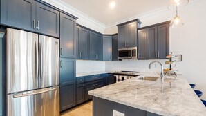 A modern kitchen with dark cabinets, stainless steel appliances, and a marble countertop. - Coastal dog-friendly gem near beach & town with pool, balcony, & central AC (Gulf Shores)