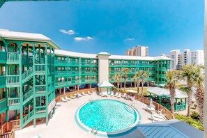 Un hôtel doté d’une piscine centrale, de nombreux balcons et offrant une vue sur les bâtiments environnants.