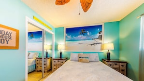 A bedroom with a bed, two nightstands, a mirror, a beach-themed painting, and a 'WELCOME HOME' sign. - Home with partial ocean view, central AC, washer/dryer & pool (Gulf Shores)