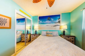 A bedroom with a bed, two nightstands, a mirror, a beach-themed painting, and a 'WELCOME HOME' sign. - Home with partial ocean view, central AC, washer/dryer & pool (Gulf Shores)