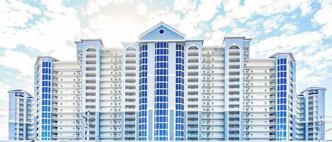 A multi-story hotel with a central atrium, balconies, and a parking area.
