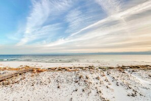 A beach with a wooden boardwalk leading to the water, sandy dunes, and a clear sky. - Roomy coastal Gulf front retreat with private Gulf-front splash pool & Gulf view (Gulf Shores)