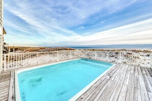 A rectangular pool with a wooden deck, surrounded by a white fence, overlooking a beach and ocean. - Roomy coastal Gulf front retreat with private Gulf-front splash pool & Gulf view (Gulf Shores)