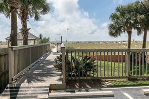 A pathway leading to a beach area with palm trees and a gazebo. - Quaint Gulf front condo with outdoor pool, hot tub, sun deck - central location (Gulf Shores)