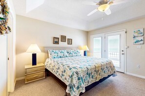 Ein Schlafzimmer mit einem Bett, zwei Nachttischlampen, einem Deckenventilator, einer Tür und einem Fenster.