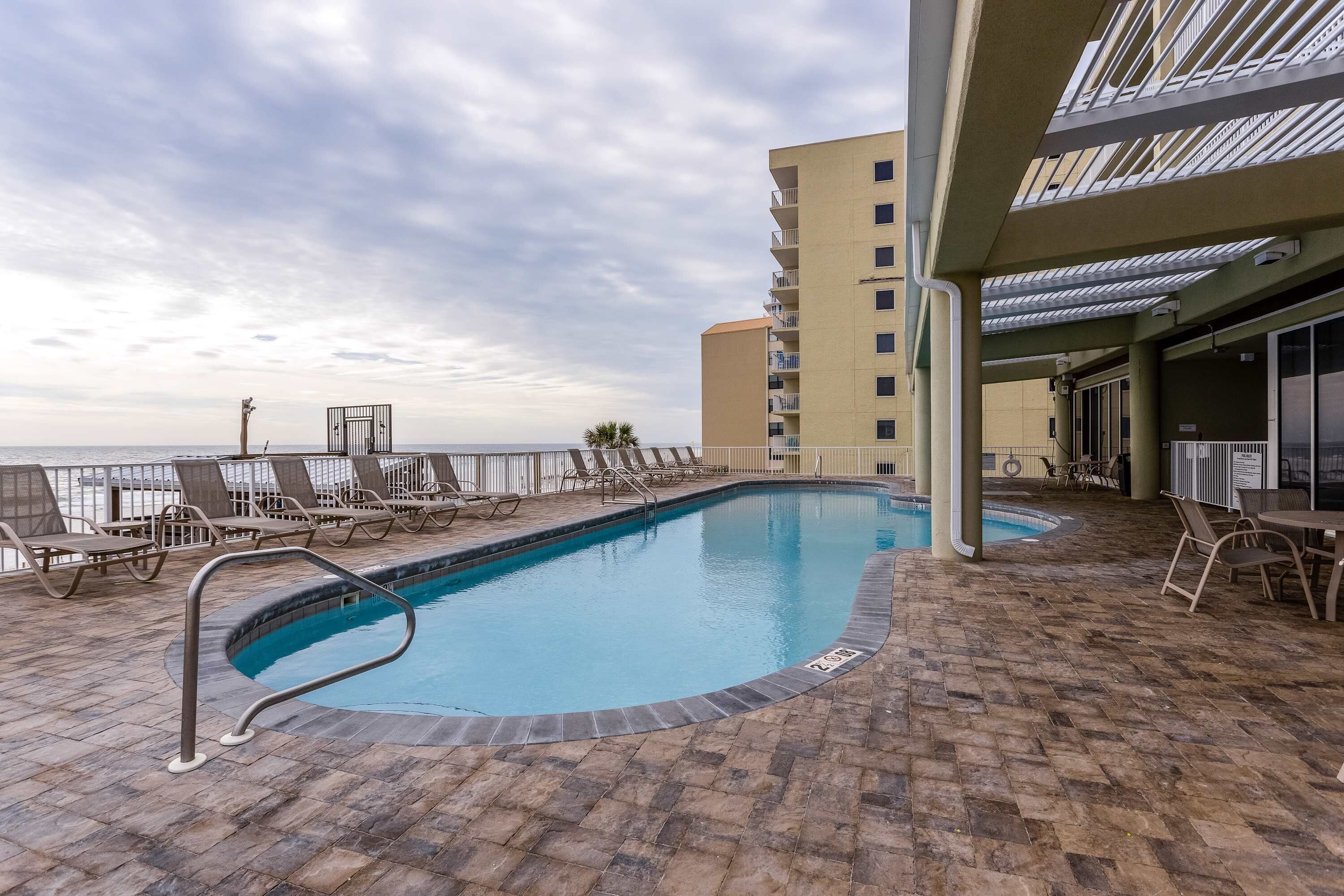 Un espace piscine comprenant des chaises longues, une piscine et un bâtiment doté de balcons.