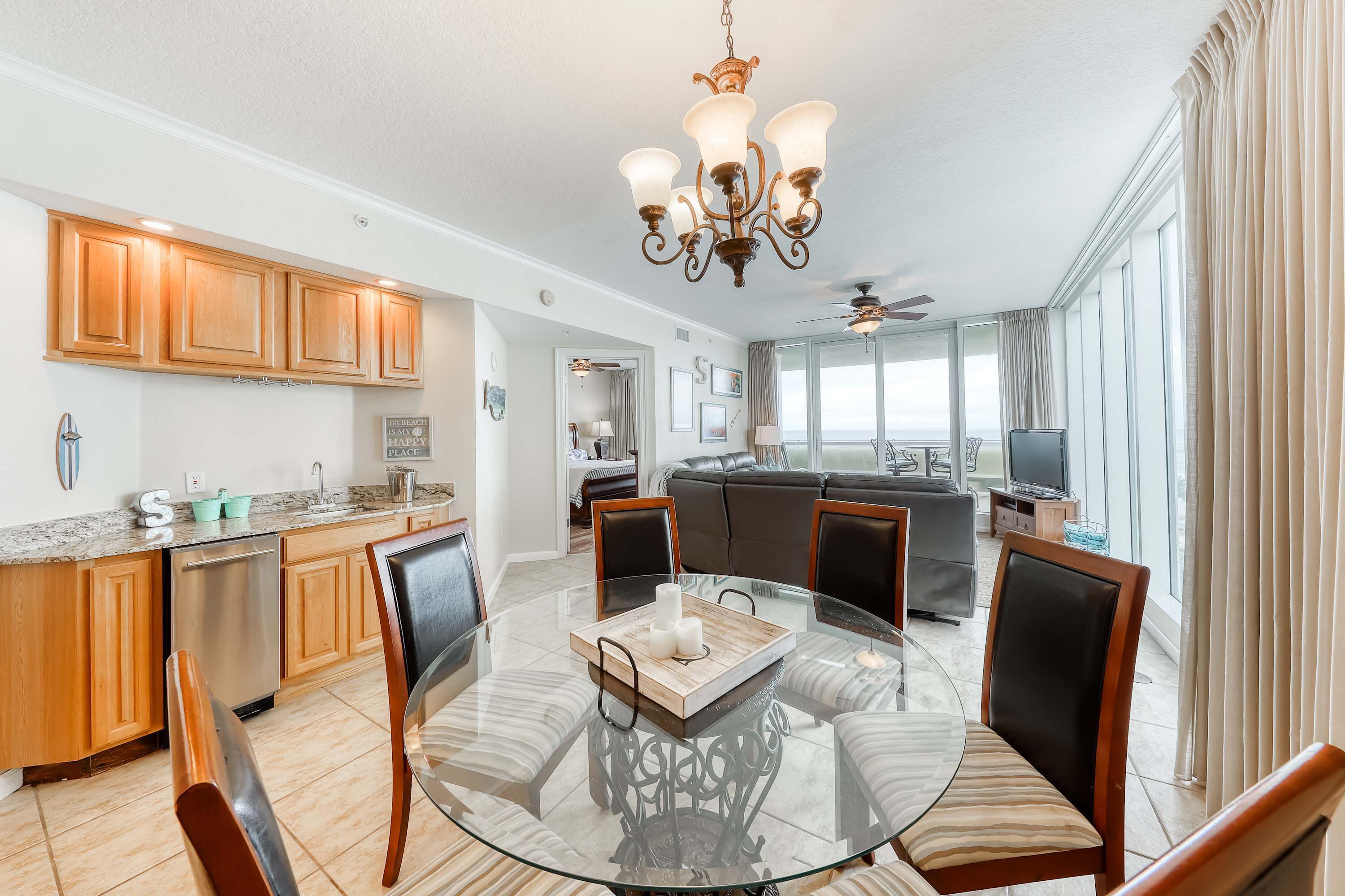 A modern kitchen with wooden cabinets, a glass dining table, and a chandelier.