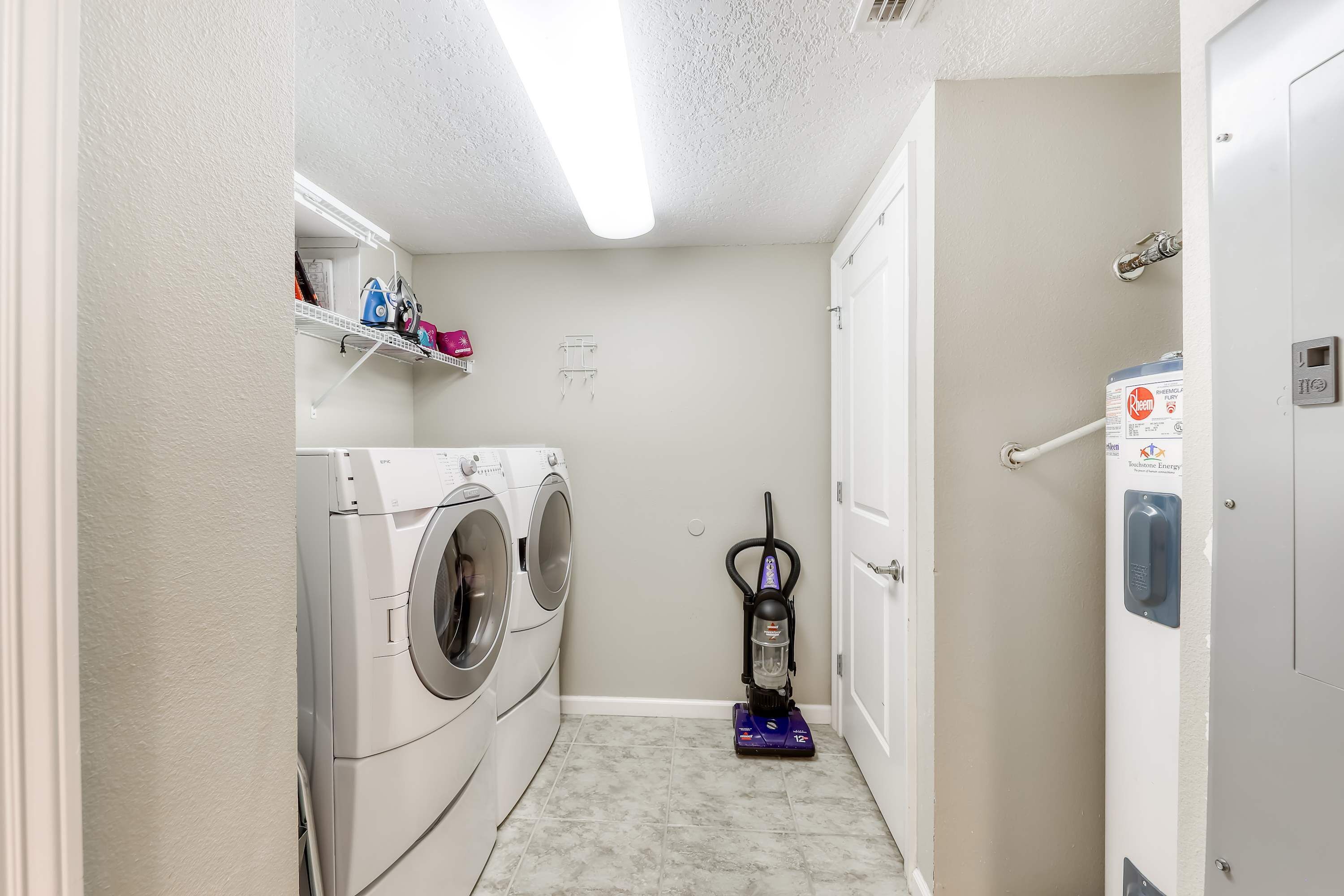 Une buanderie équipée d’un lave-linge, d’un sèche-linge et d’un aspirateur.