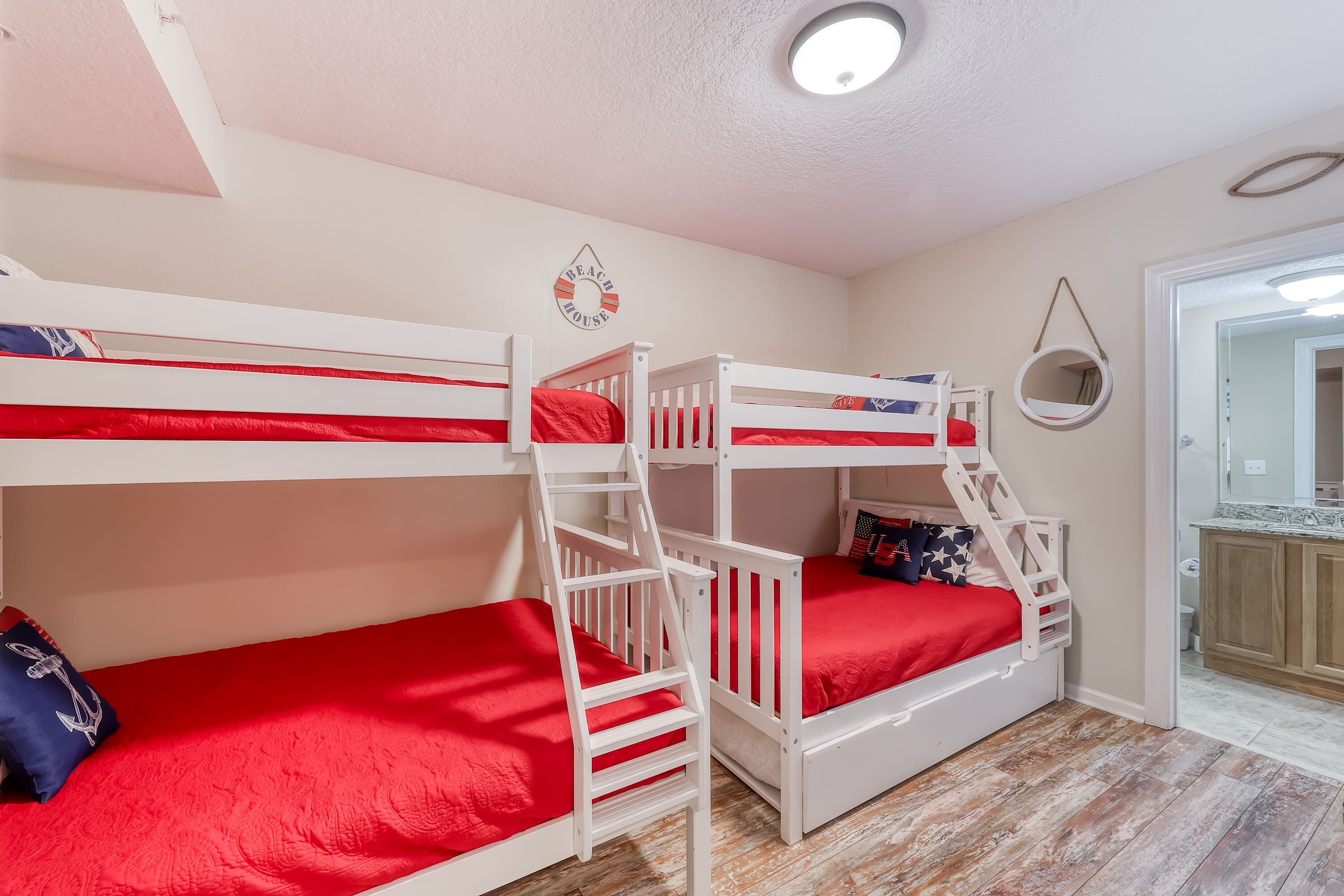 Ein Zimmer mit Etagenbetten, einem kleinen Spiegel und einer Tür zu einem Badezimmer.