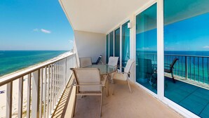 Een balkon met een glazen deur, een ronde tafel en twee stoelen.