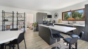 A modern kitchen with a central island, bar stools, and a dining table. - Villa with Pool, Spa, and Sauna (Saint-Nazaire-d'Aude)