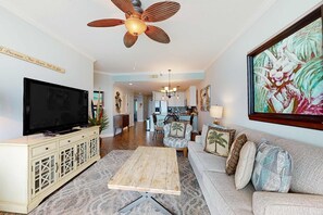 Ein Wohnzimmer mit Fernseher, Deckenventilator, Sofa und einem Gemälde.