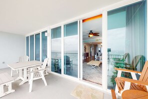 Ein Balkon mit Tisch und Stühlen, einem Deckenventilator und Blick ins Innere.
