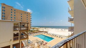 A hotel with a pool, beach view, and multiple balconies. - Beachfront condo with balcony overlooking Gulf of Mexico & resort pool (Gulf Shores)