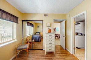Une pièce comprenant un lit, une commode, une chaise, une table à manger et un coin buanderie.