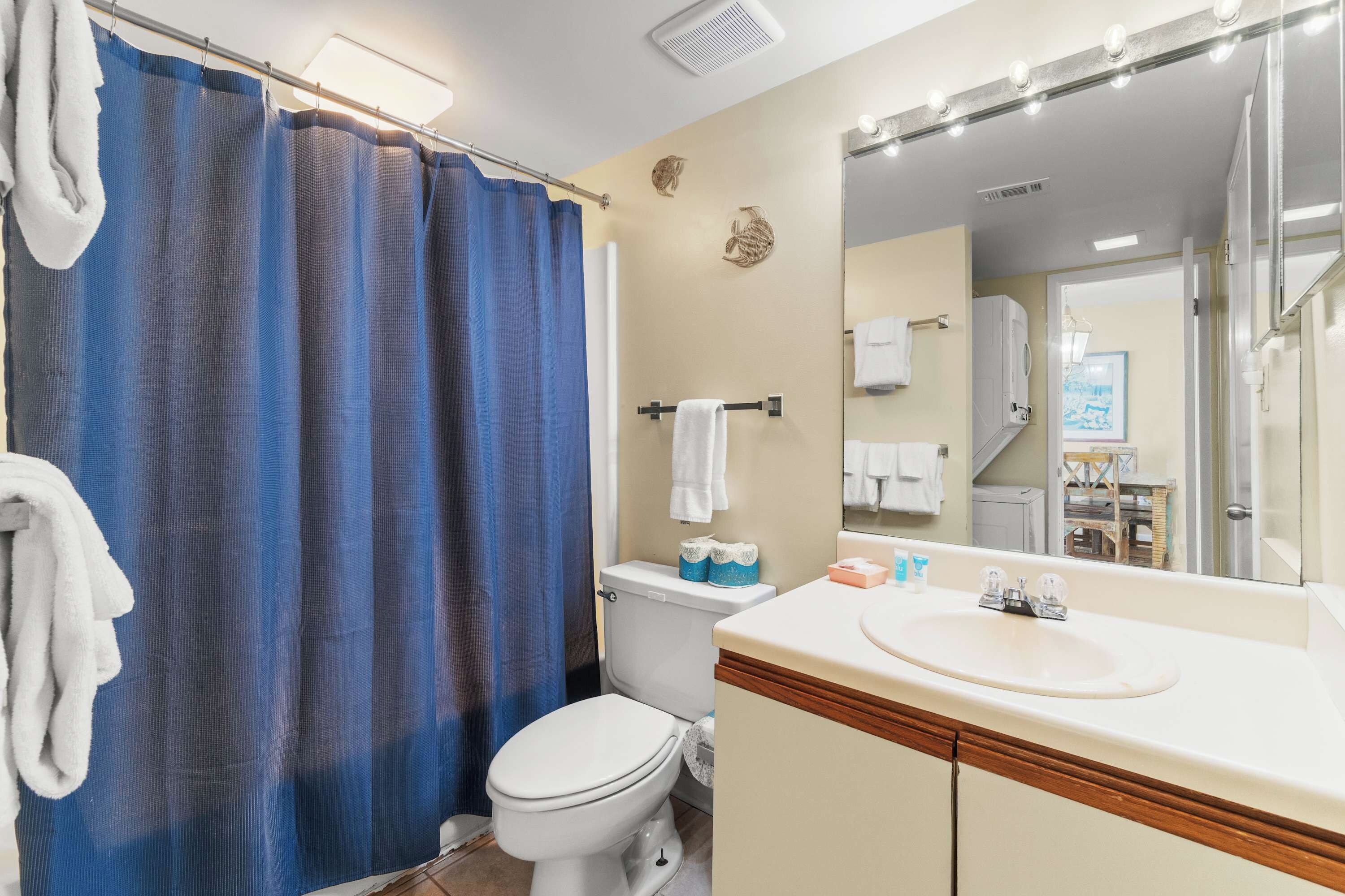Une salle de bain avec un rideau de douche, des toilettes, un lavabo et un miroir.