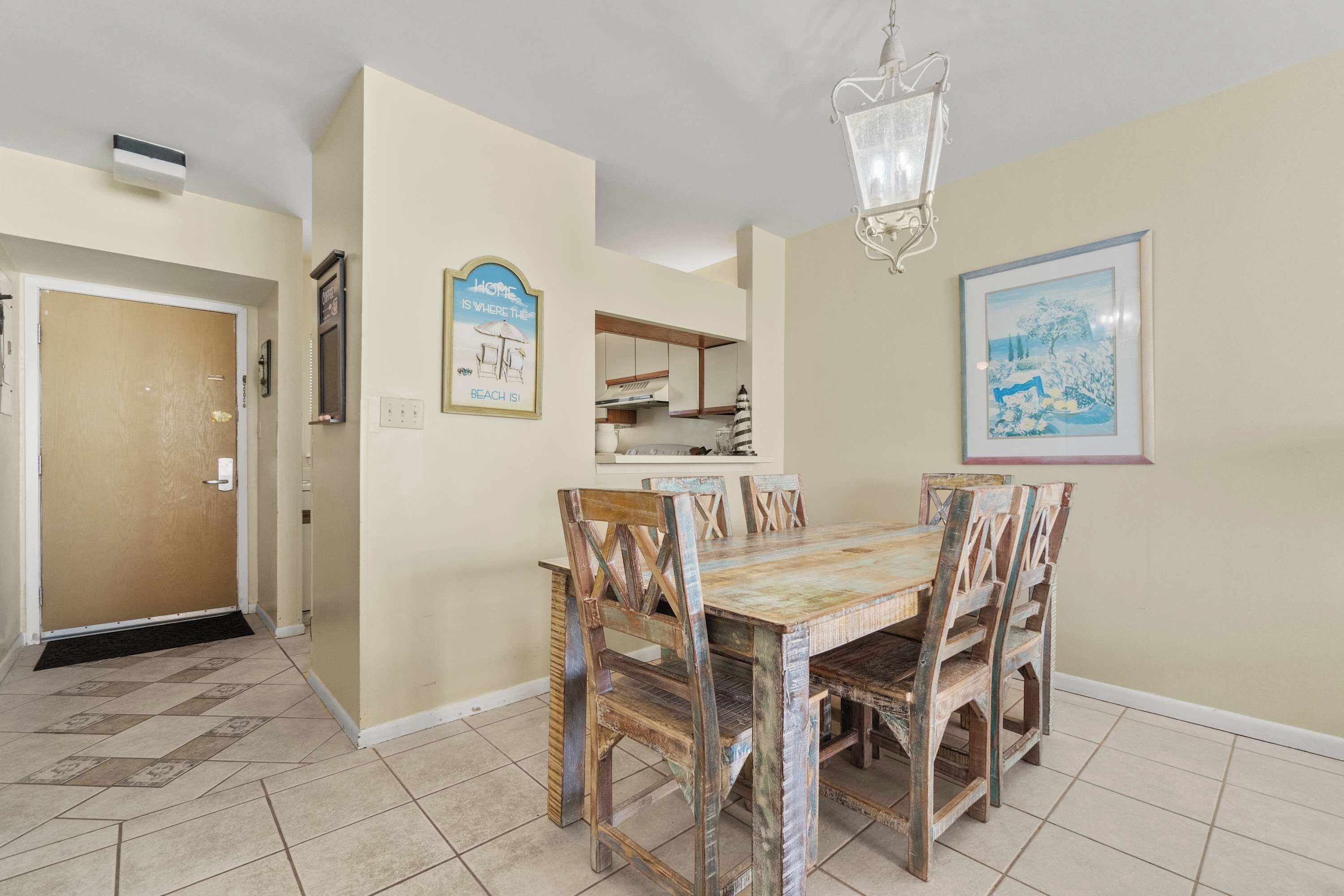 A dining area with a wooden table and chairs, a chandelier, and a framed picture on the wall.