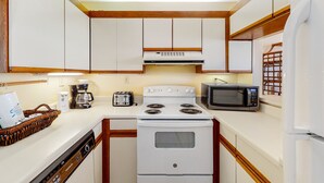 A kitchen with white cabinets, a stove, a microwave, and a coffee maker. - Beachfront condo with balcony overlooking Gulf of Mexico & resort pool (Gulf Shores)