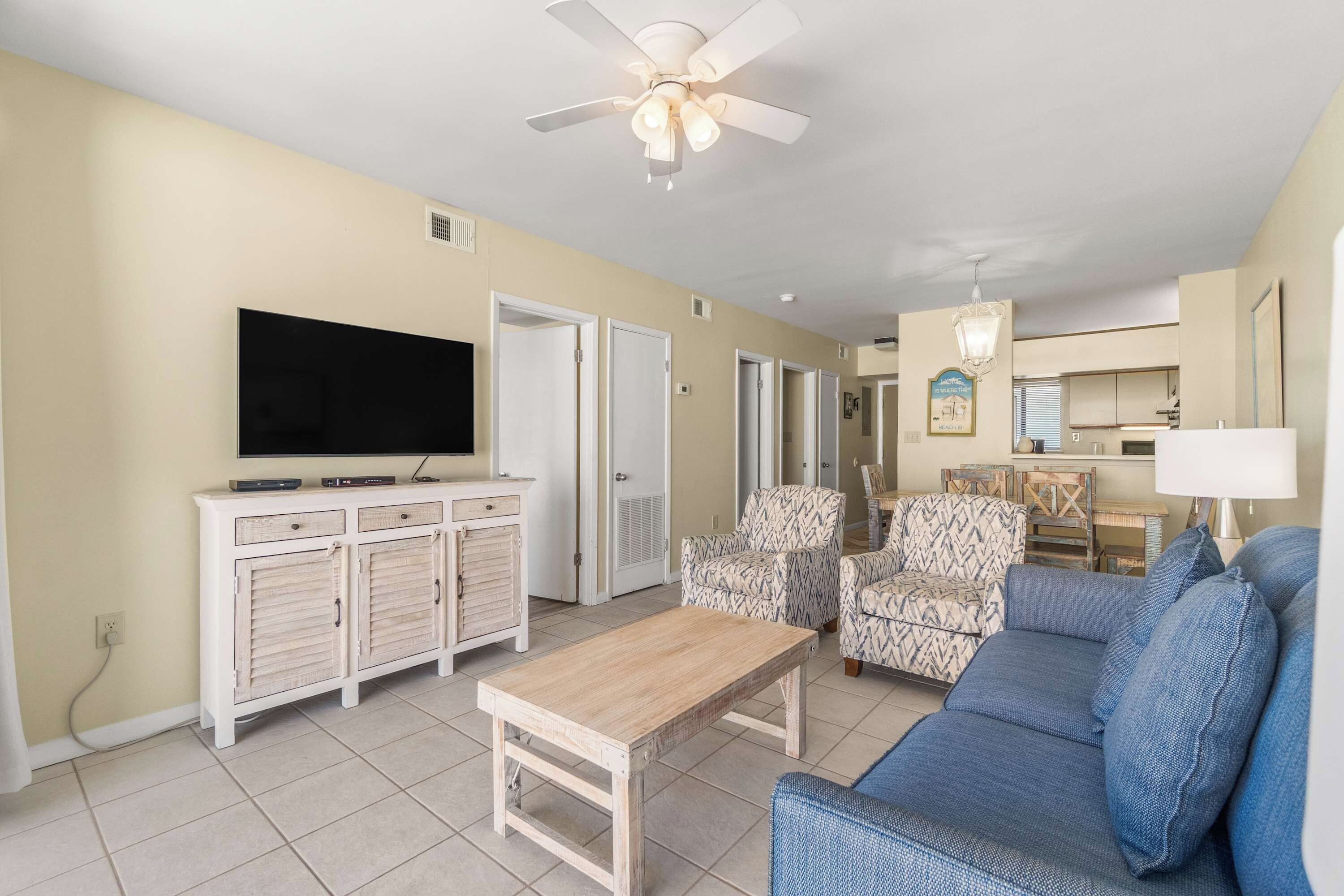 A living room with a television, a ceiling fan, and a sofa.