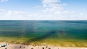 Una playa con agua cristalina, gente y sombrillas.