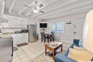 A compact kitchen with modern appliances, a dining area with a table and chairs, and a ceiling fan. - Ocean-view condo with pool access, outdoor seating, central AC & WiFi (Gulf Shores)
