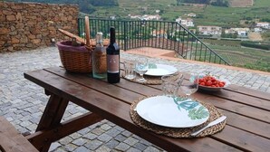 A wooden picnic table set outdoors with a scenic view of rolling hills and houses in the background.