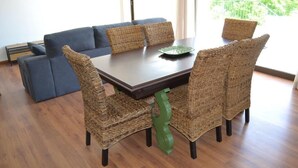 A dining area with a dark wooden table, wicker chairs, and a blue sofa.