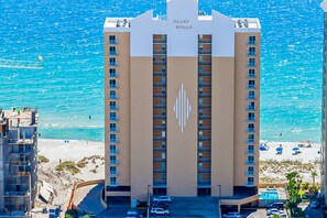 Ein Hochhotel mit einem zentralen Atrium, mehreren Balkonen und Blick auf den Strand.