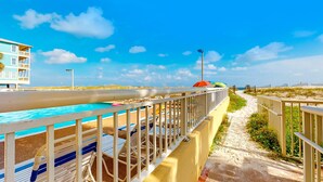 Et hotel ved stranden med pool, liggestole og sti ned til stranden.