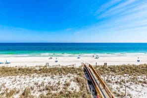 Une plage avec une promenade en bois menant au rivage, une plage de sable et l’océan.