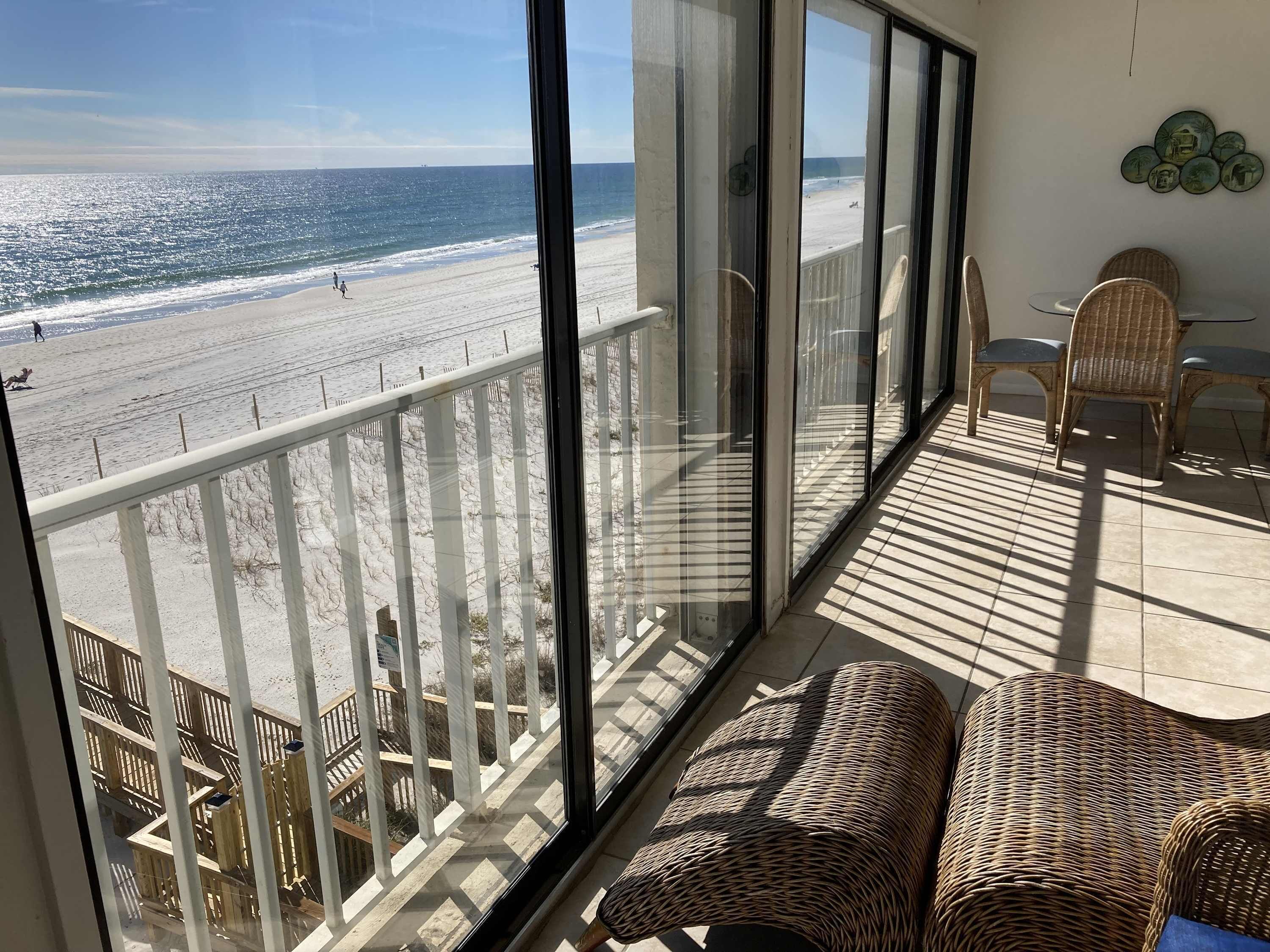 Ein Balkon mit Blick auf den Strand, Korbmöbel und eine Essecke mit Stühlen und einem Tisch.