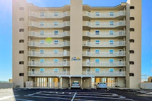 Un hôtel à plusieurs étages, doté d’une entrée principale, de balcons à chaque étage et d’un parking situé à l’avant.