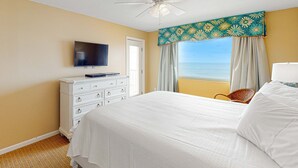 A hotel room with a bed, a television, a dresser, a ceiling fan, and a view of the ocean. - Beachfront Condo with Shared Outdoor Pool, Central AC, Private Balcony, Views, WiFi (Gulf Shores)