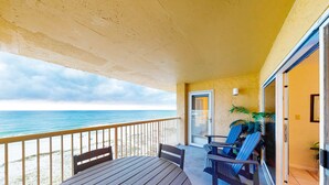 A balcony with a view of the beach, a table, chairs, and a door leading to an interior space. - 5th-floor beach-front condo with balcony, great views, & pool access (Gulf Shores)