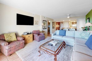 Ein Wohnzimmer mit einer Couch, einem Sessel, einem Couchtisch und einem Fernseher.