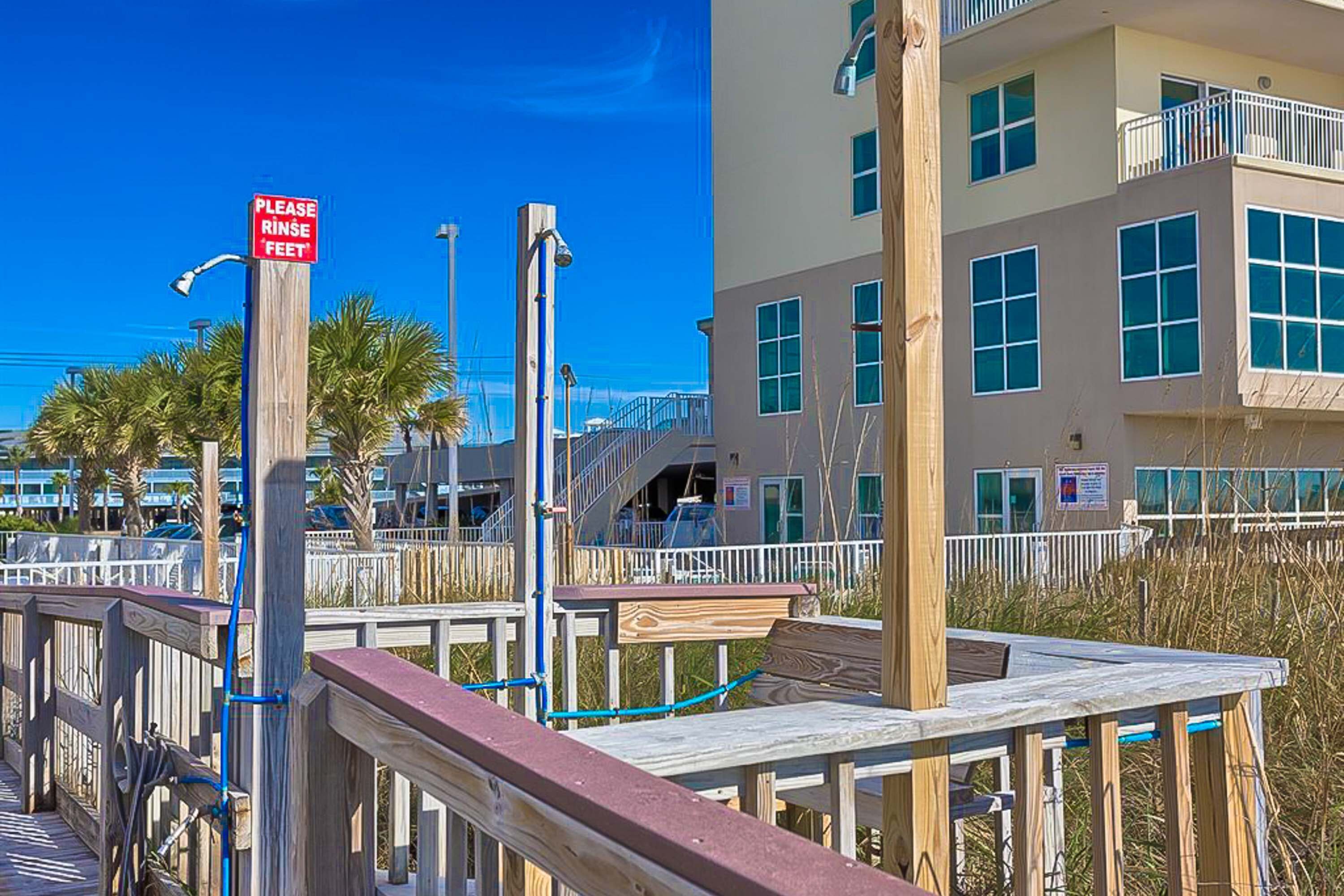 A wooden boardwalk with a sign that reads 'PLEASE RINSE FEET'.