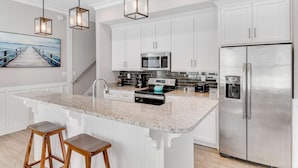 A modern kitchen with white cabinetry, a granite countertop, stainless steel appliances, and pendant lighting. - 2-Story Beach House w/Balcony, Washer/Dryer, Shared Pool, Snowbird-Friendly (Gulf Shores)