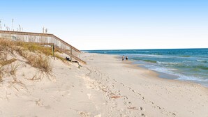 A beach with a wooden walkway leading to the water, sandy beach, and footprints. - 2-Story Beach House w/Balcony, Washer/Dryer, Shared Pool, Snowbird-Friendly (Gulf Shores)