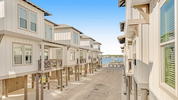 A beachfront property with multiple levels of wooden structures supported by stilts, a paved walkway, and a view of the sea. - 2-Story Beach House w/Balcony, Washer/Dryer, Shared Pool, Snowbird-Friendly (Gulf Shores)