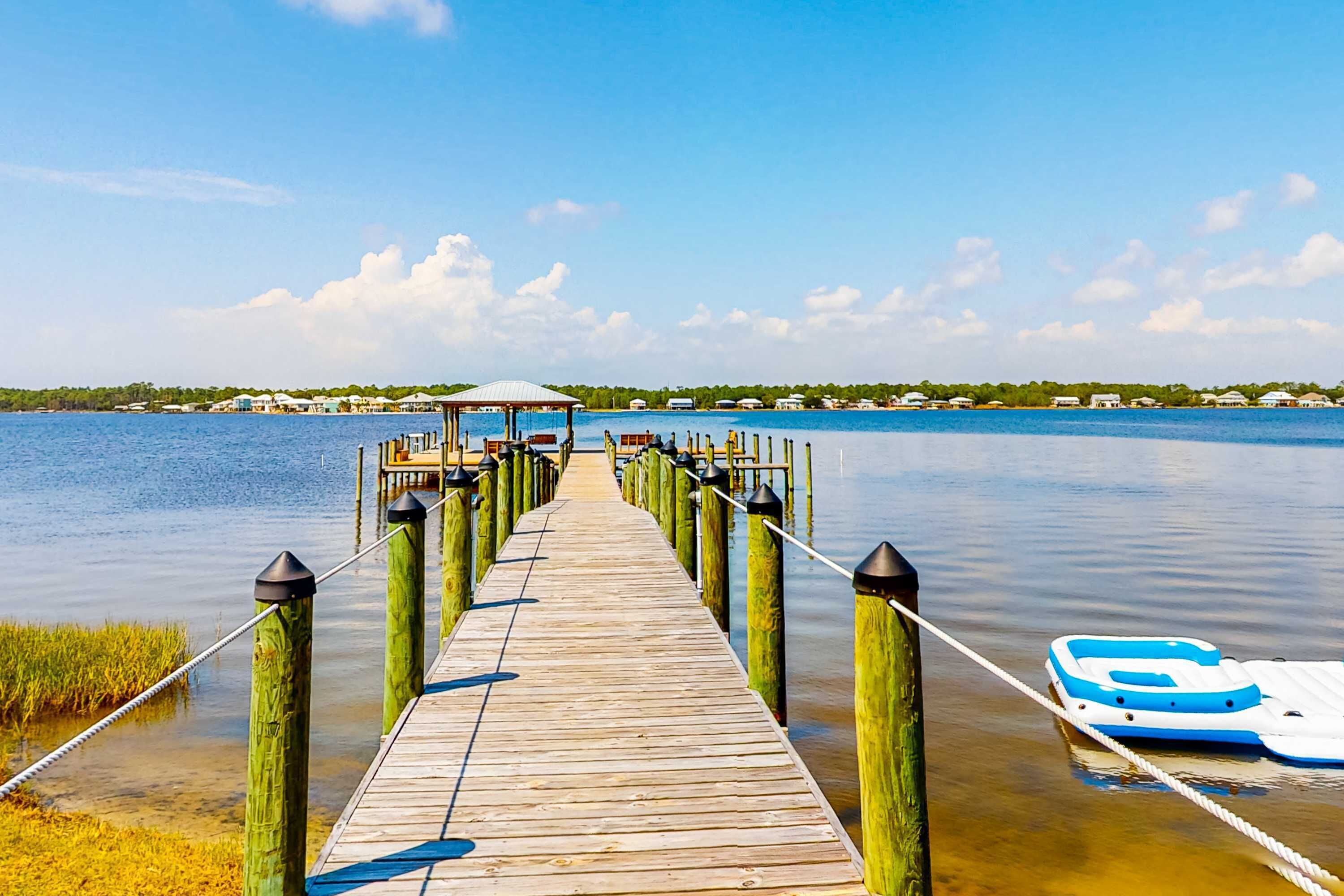 A wooden pier leading to a gazebo over water, with a boat docked nearby.