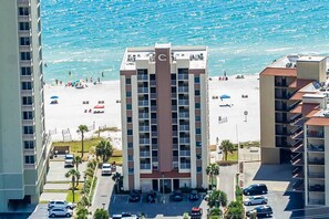 A multi-story hotel with a central entrance, parking lot, and a beach view. - Gulf-front condo on 5th floor with amazing views, on-site pool & balcony (Gulf Shores)