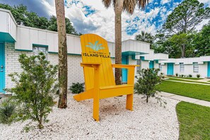 Una silla amarilla con un letrero que dice 'The Iconic Island Villa' frente a un edificio de paredes blancas y detalles azules.