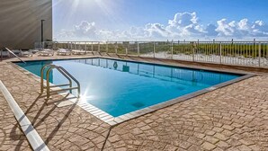 A swimming pool with a sunlit sky and a view of the beach. - Recently renovated 5th-floor oceanfront condo with pool, ocean view & WiFi (Gulf Shores)
