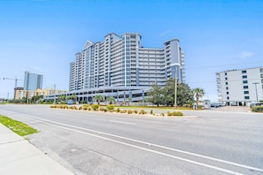 A multi-story hotel with a modern architectural design, featuring a prominent entrance and a parking area. - Gulf-Front Condo w Great Beach Views, Balcony & Shared Pools, Hot Tubs & Sauna (Gulf Shores)