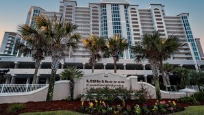 Un hotel de varios pisos con un letrero llamativo que dice 'Lighthouse Condominiums'.