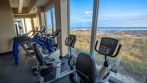 Un gimnasio con máquinas de cardio y vista al mar.