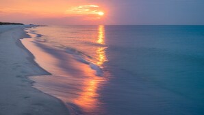 Una playa con un atardecer sobre el océano.