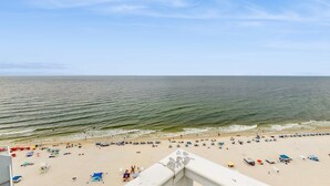 Ein Strand mit Sonnenschirmen und Liegestühlen, ein klarer Himmel und ruhiges Meer.