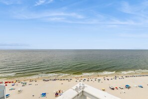 A beach with umbrellas and lounge chairs, a clear sky, and calm sea. - Gulf-Front Condo w Great Balcony, Ocean View, AC & Shared Pools, Hot Tubs & Gym (Gulf Shores)