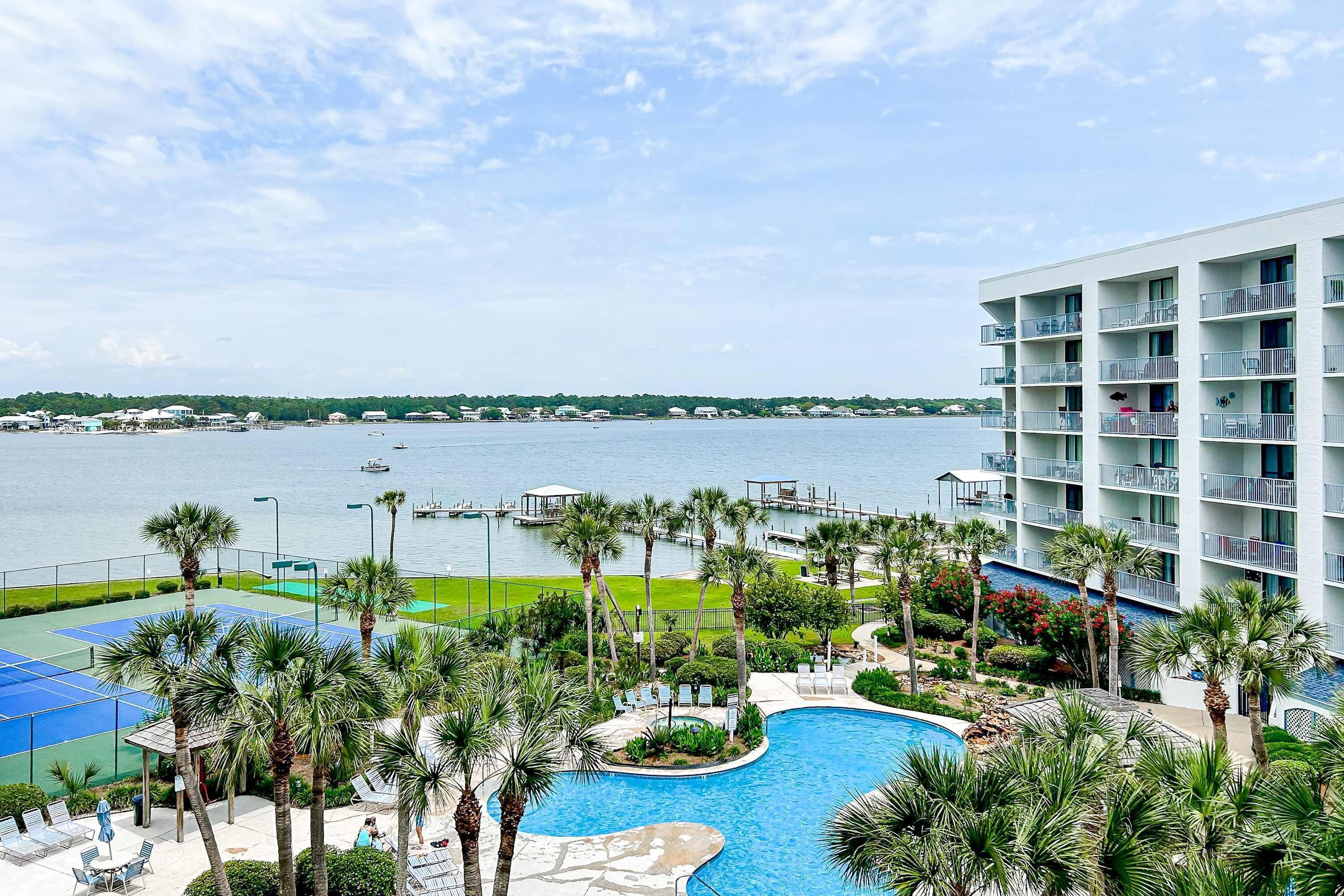 Ein Hotel mit Pool, Palmen und Blick auf das Wasser.